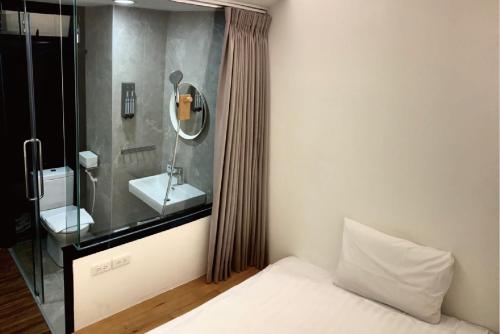 - une chambre avec un lavabo, un miroir et un lit dans l'établissement Norden Ruder Hostel Taitung, à Taïtung